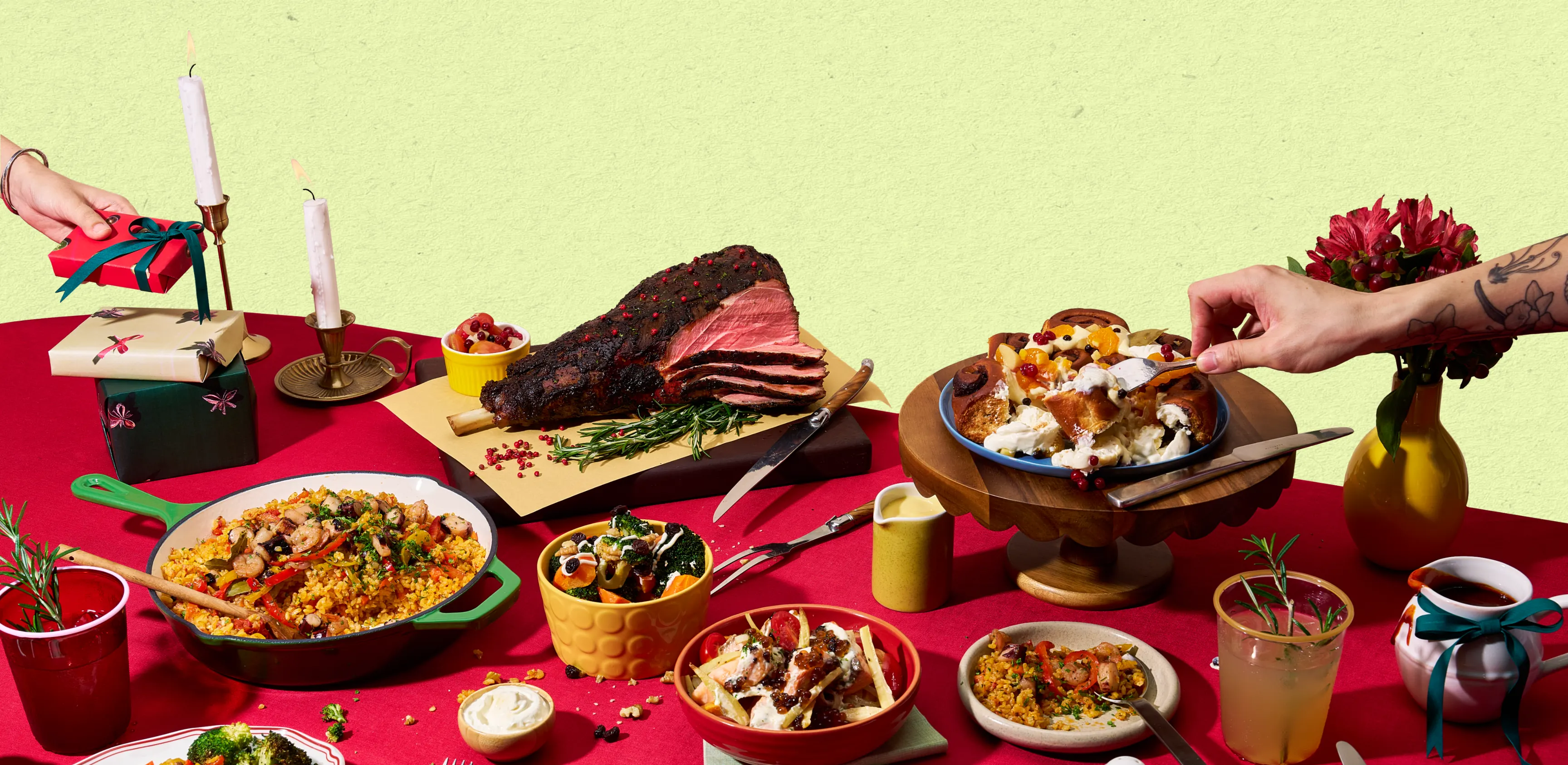 A Christmas table laid with roast, paella, sides and candles